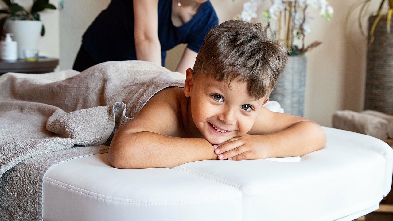 Familienurlaub mit Abenteuer, Wellness & Co. im Elldus Resort - Familotel Erzgebirge Im Spa Bereich des Elldus Resort freut sich ein junger Gast einer Kindermassage mit Hörspiel.